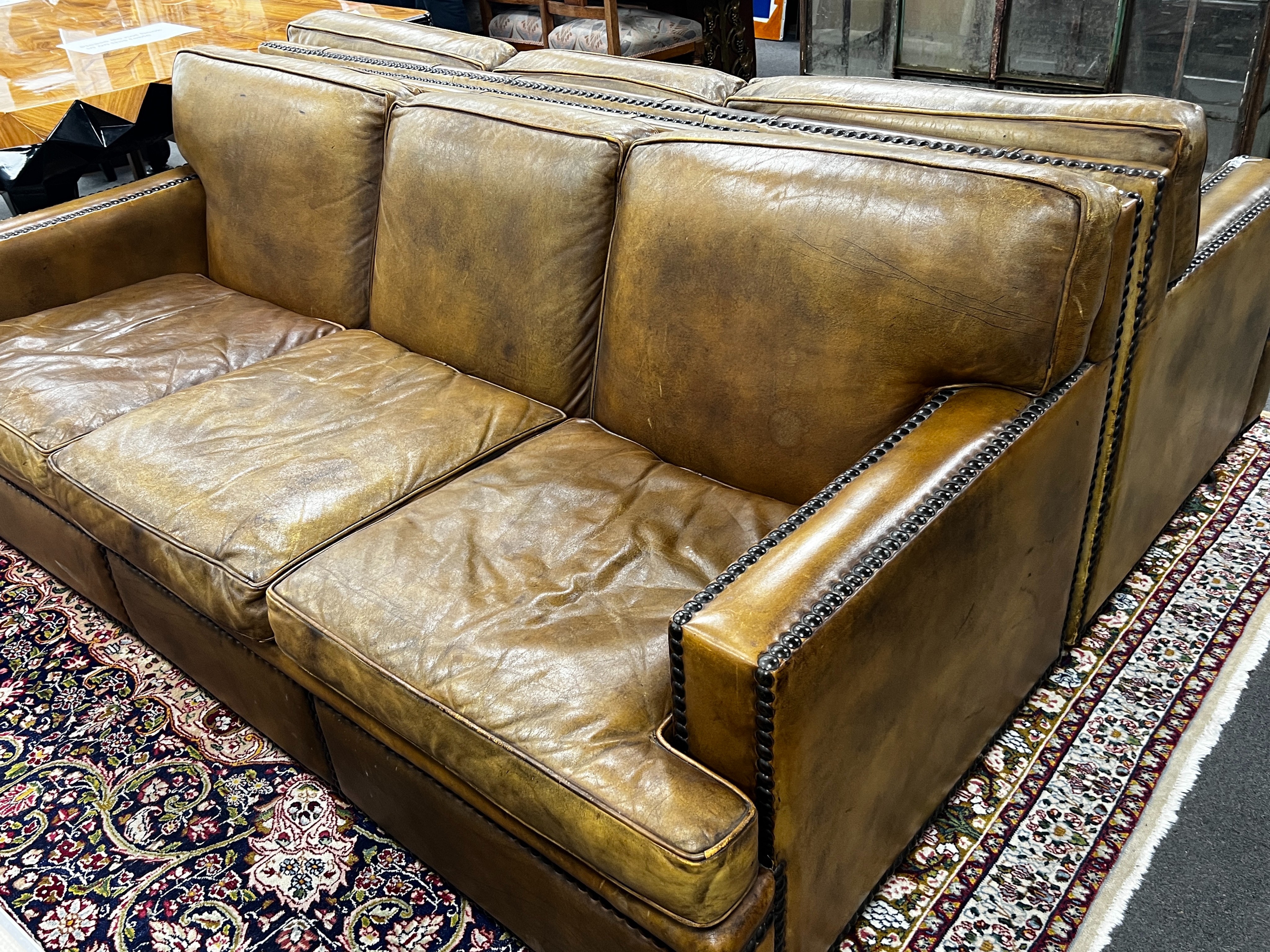 A pair of brown leather brass studded three seater settees, length 200cm, depth 90cm, height 84cm